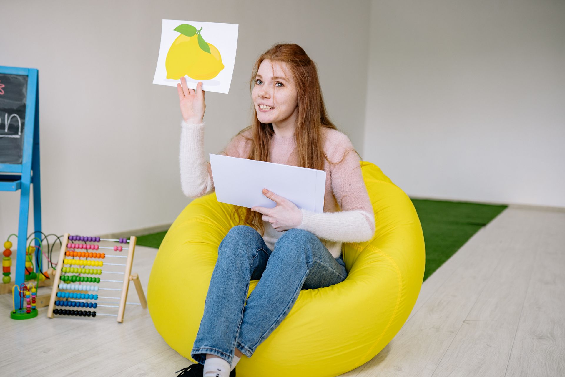 A therapist holds up a picture card in a colorful clinic playroom with learning toys