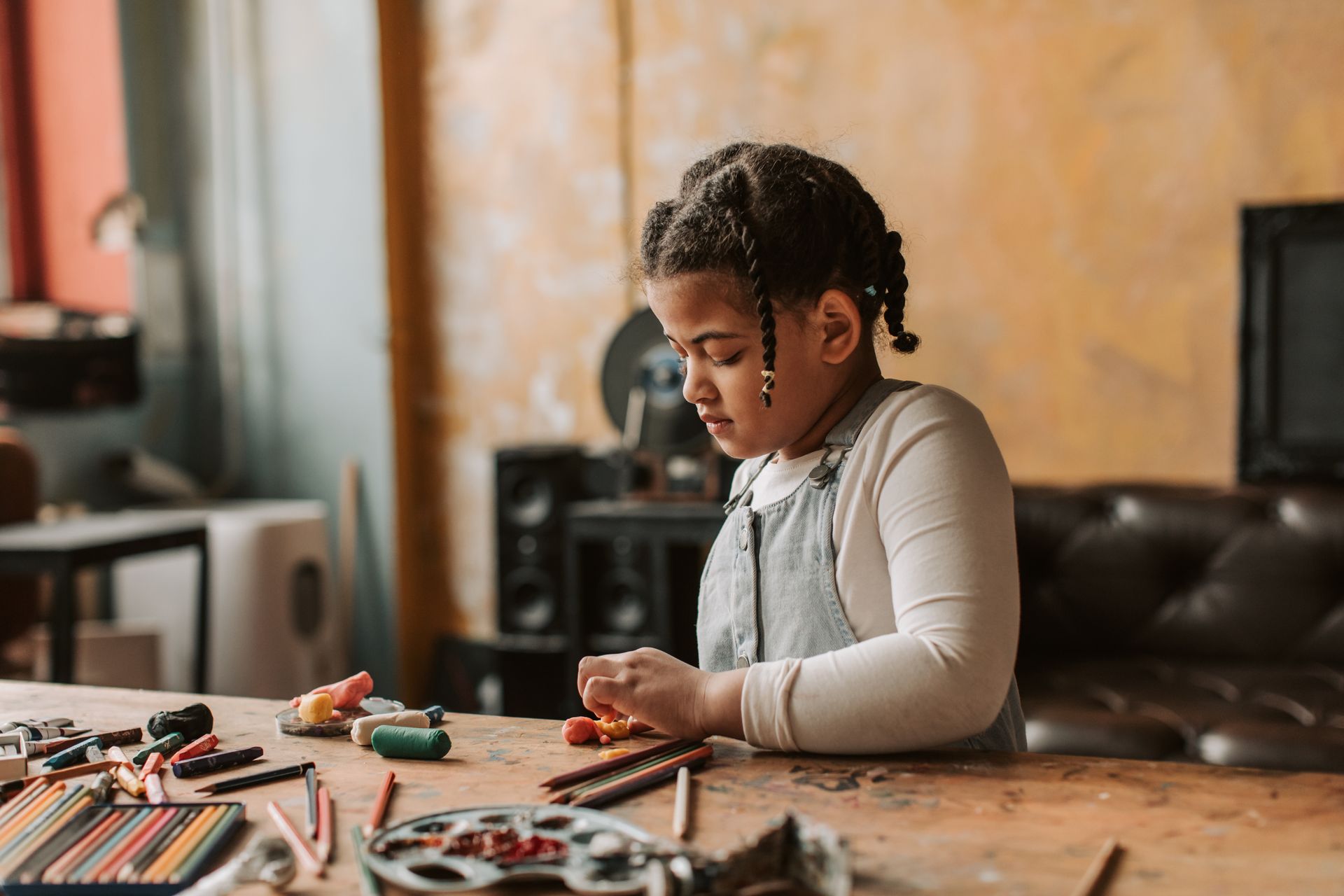 A young girl concentrates on a hands-on craft activity at a work table
