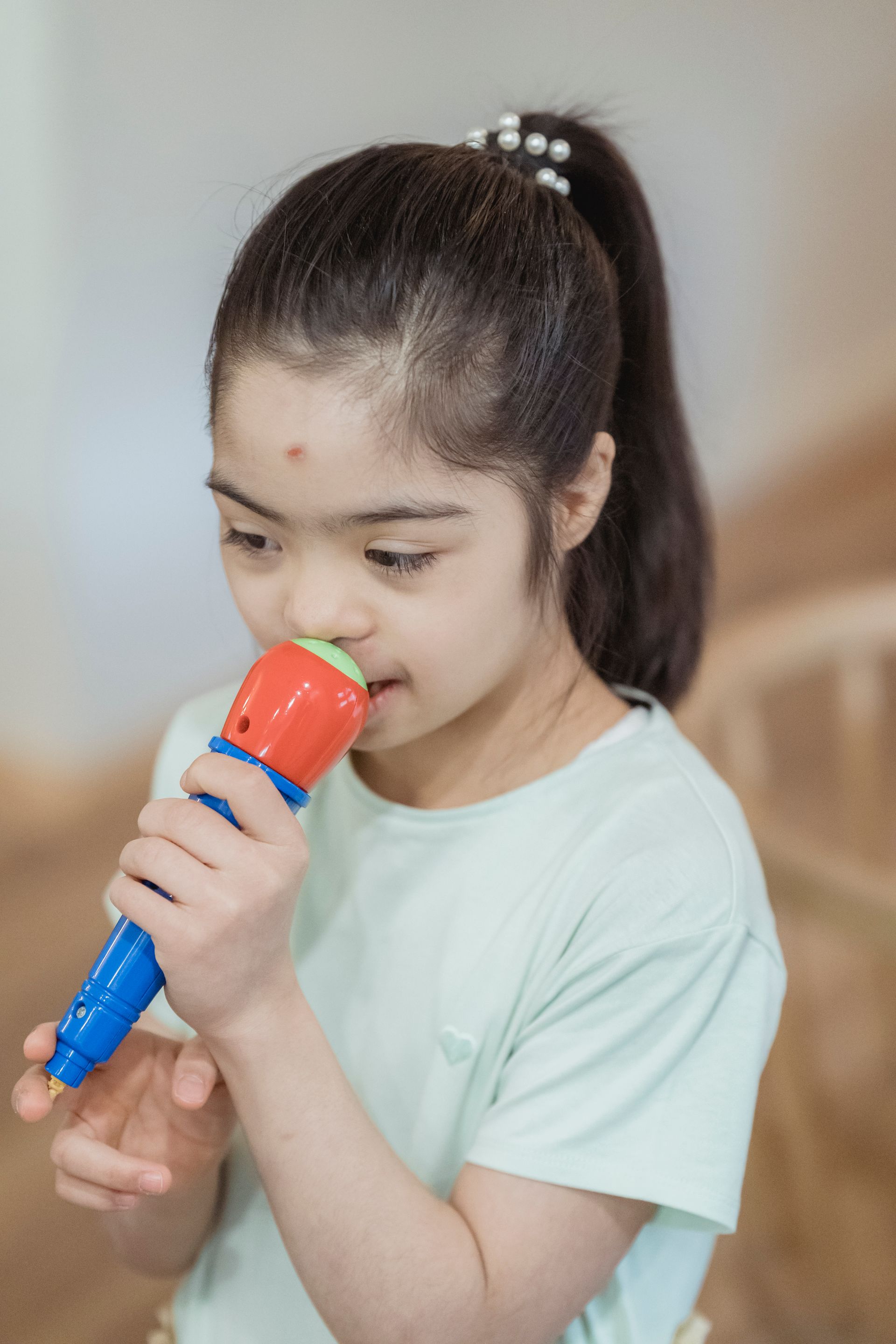 A young girl practices speaking into a toy microphone during a therapy session